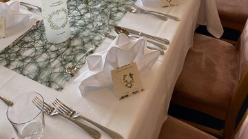 An elegantly set table with white tablecloths and decorative napkins. In the center are candles and flowers that create a festive atmosphere.