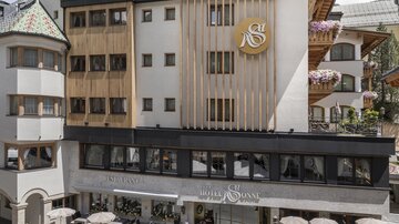 A modern hotel building with an appealing design. In the foreground, seating areas and decorative plants can be seen.