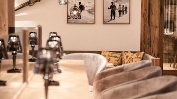 A cozy restaurant with wooden decor and comfortable seating. Black and white photos of people in the snow hang on the wall.