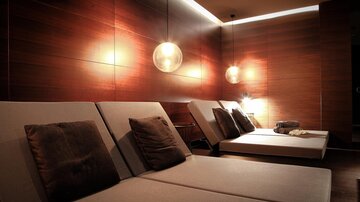 A relaxing wellness area with comfortable loungers and soft lighting. The wooden paneling creates a warm and peaceful atmosphere.