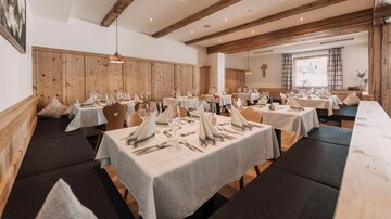 An inviting restaurant with wooden walls and elegantly set tables. The atmosphere is cozy and friendly.