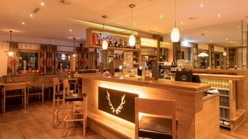 Eine gemütliche Bar mit Holzinterieur und warmem Licht. Die Theke ist gut ausgestattet und einladend für Gäste.