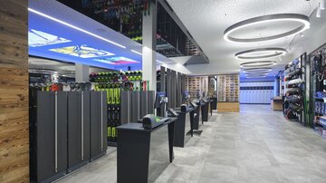 A modern sports retail space with a bright atmosphere. On the left side, ski equipment and a spacious cash register can be seen.