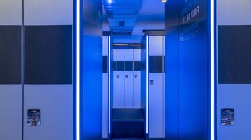 A modern corridor with blue light accents. On the left and right, there are lockers in an elegant design.
