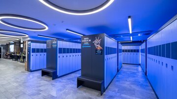 A modern changing area with blue lockers and stylish lighting. The walls are kept in neutral tones, creating an inviting atmosphere.
