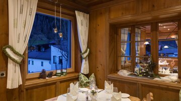 A cozy dining area with wooden paneling and traditional design. The table is set and the lighting creates an inviting atmosphere.