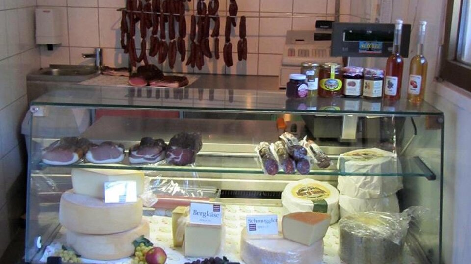 A refrigerator with various types of cheese, cold cuts, and some bottles. The selection looks fresh and inviting.