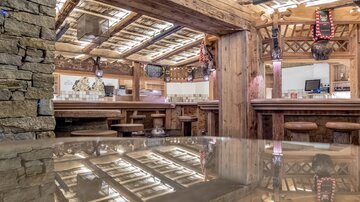 A cozy restaurant with wooden-paneled interior and an inviting bar. The space has a warm atmosphere and reflects the rustic design.