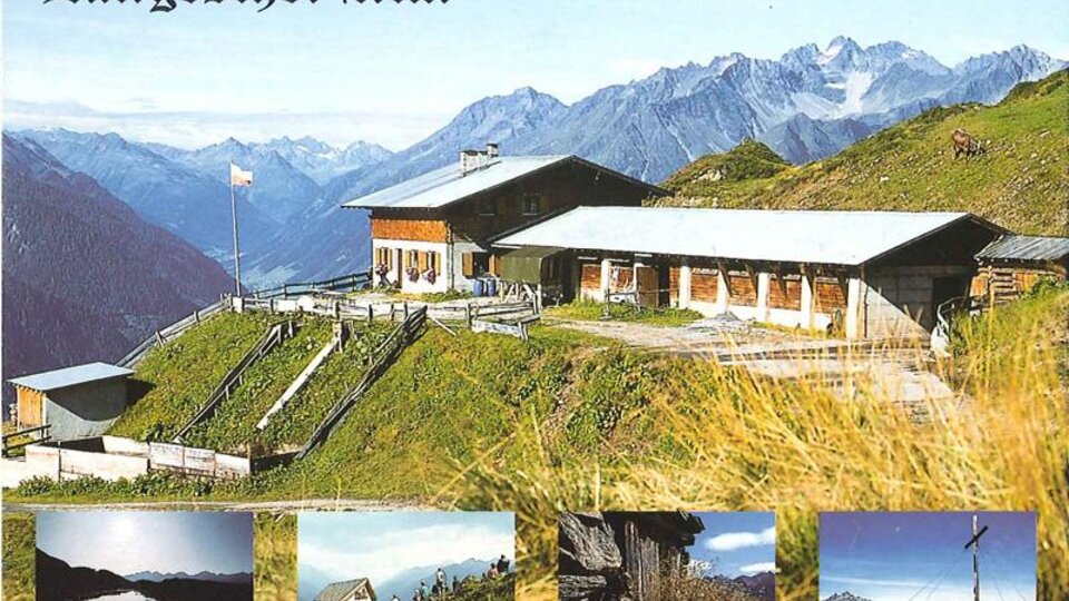 A picturesque alpine pasture surrounded by tall mountains and green meadows. In the foreground, the building of the Langesthei Alm can be seen.