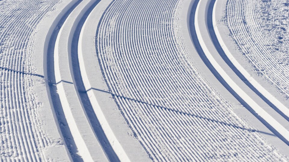 A freshly groomed cross-country ski trail in the snow. The tracks wind gracefully through the winter landscape.