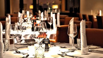 An elegantly set table in a stylish restaurant. Glasses, cutlery, and decorative details are carefully arranged.
