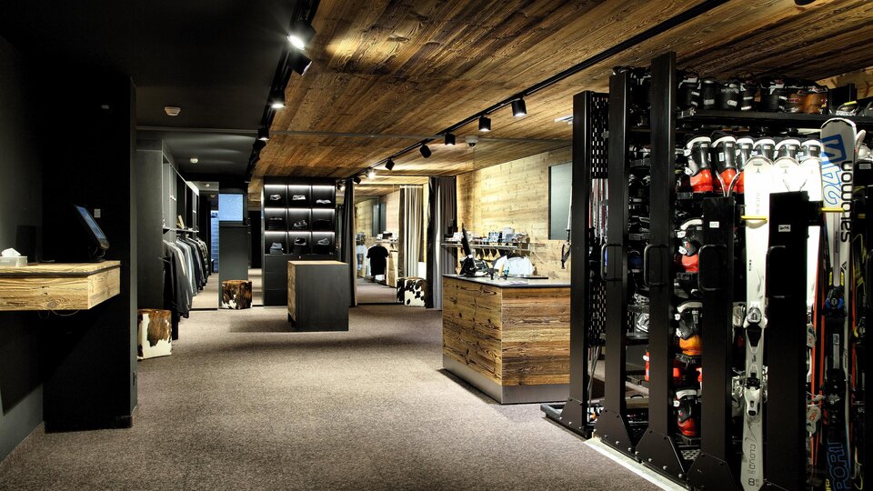 A modern sports store with wooden ceilings and elegant display shelves. Ski equipment is prominently displayed.