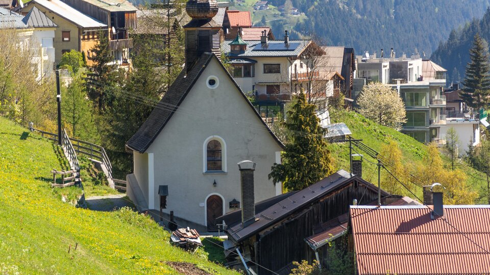 A picturesque village in the mountains with a small church. The surroundings are green and surrounded by impressive hills. | © Bernhard Gruber – Photography