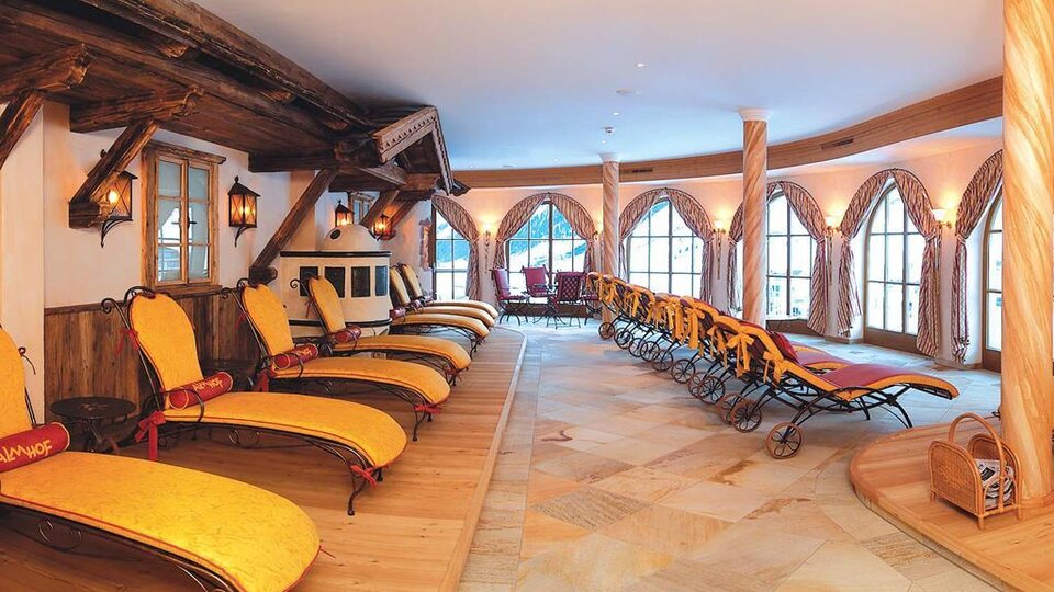 A relaxing wellness area with loungers and large windows. The cozy atmosphere is accentuated by the wooden details and soft lighting.