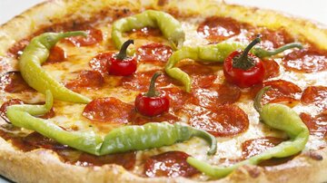 A delicious pizza with pepperoni and fresh chilies. The colorful chilies give it a special touch.