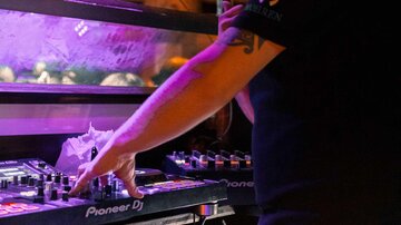 A DJ navigates his music on a Pioneer DJ setup. The colorful lights create a vibrant atmosphere.