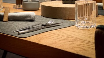 A stylish table in a restaurant with a bottle of wine and glasses. The warm lighting conditions create a cozy atmosphere.