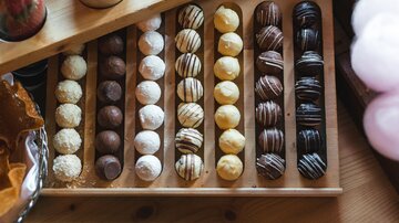 A selection of delicious chocolates in various flavors. The chocolates are neatly arranged on a wooden board.