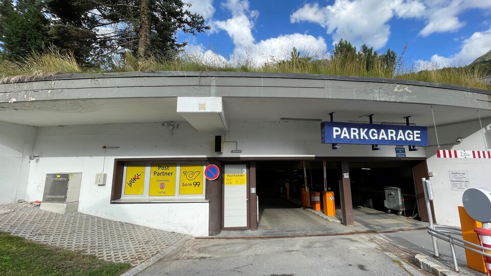 A parking garage with an entrance and a sign that reads "PARKGARAGE". The sky is blue with some clouds.