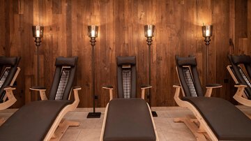 A relaxing room with wooden paneling and cozy loungers. Soft lighting creates a calming atmosphere.