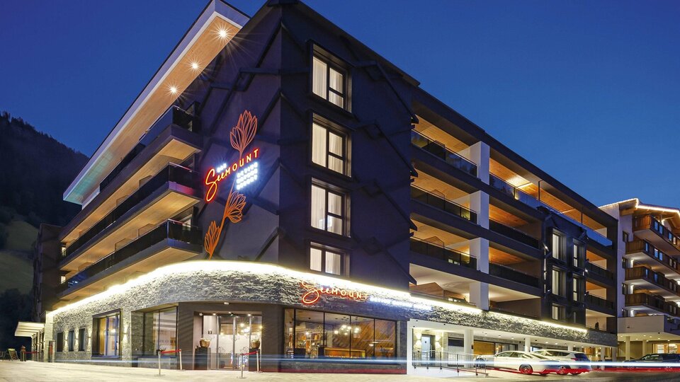 A modern hotel building at night with a illuminated facade. The windows reflect the atmospheric light of the surroundings.