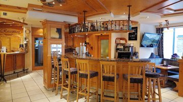 Eine gemütliche Bar mit Holzverkleidung und Hockern. Die Atmosphäre ist einladend und freundlich.