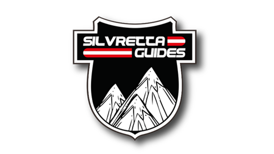 A logo with the name "Silvretta Guides". It features stylized mountains on a black shield.