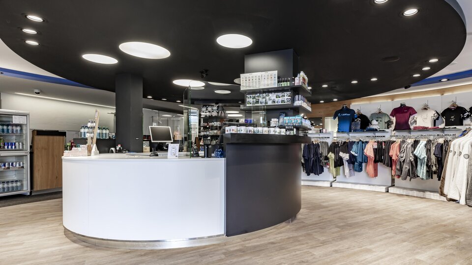 A modern sales area with a round reception desk and a clothing display. The walls are light-colored, and the lighting is friendly and inviting.
