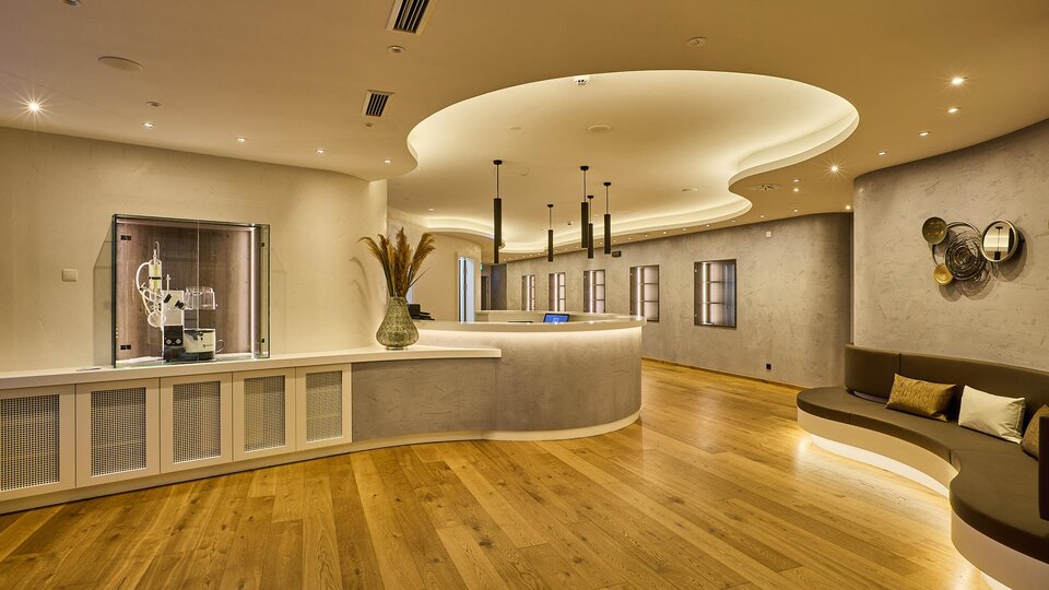 A modern reception area with stylish design and bright wooden floors. The walls are painted in soft color tones, and the lighting creates a pleasant atmosphere.