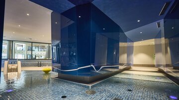 Ein moderner Wellnessbereich mit blauen Wänden und einem Pool. Die Umgebung wirkt entspannend und einladend.