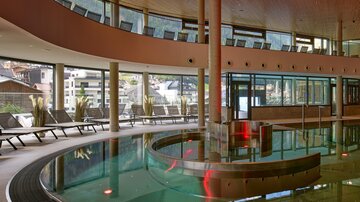 Ein modernes Spa mit einem klaren Schwimmbecken und gemütlichen Liegen. Weite Fenster bieten einen schönen Blick auf die Umgebung.