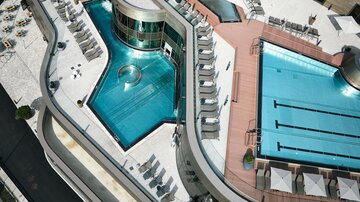 Ein modernes Hotel mit zwei Swimmingpools und zahlreichen Liegen. Die Architektur ist elegant und einladend.