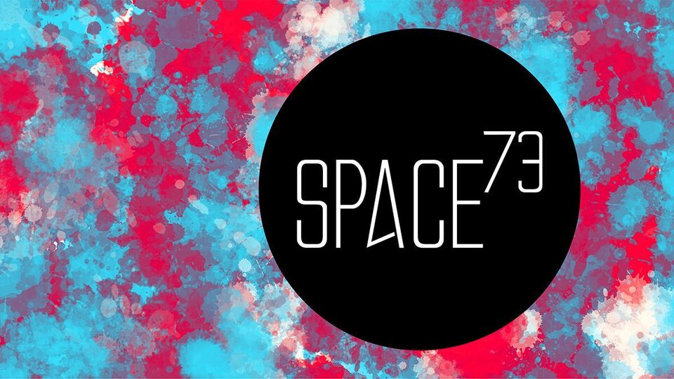 A striking, colorful background pattern in blue and red. The logo "SPACE73" in the center is black and has a modern design.