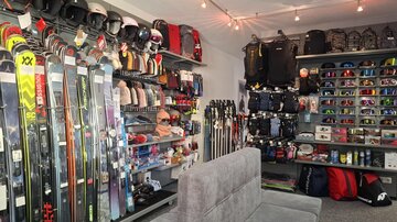 A well-organized ski shop with various skis, helmets, and clothing. In the background, a variety of accessories and equipment for winter sports can be seen.