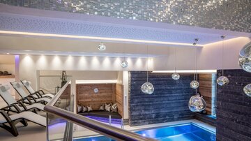 A modern wellness area with an indoor pool and relaxation loungers. Soft lighting creates a relaxing atmosphere.