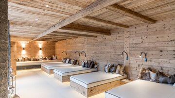 A cozy room with wooden paneling and several loungers. Soft light creates a relaxed atmosphere.