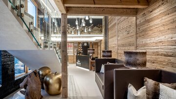 A modern and stylish interior with wooden paneling and elegant furniture. Large windows let in plenty of light and create an inviting atmosphere.