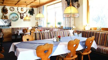A cozy restaurant with wooden furniture and colorful benches. The room is bright and inviting, with decorative hunting trophies on the walls.