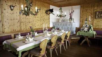 A cozy restaurant with wooden walls and rustic decor. Tables are lovingly set, and a warm atmosphere invites you to linger.