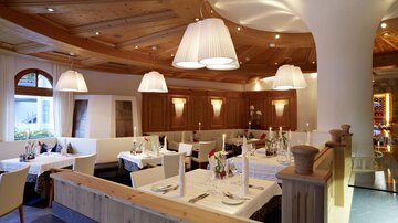 A stylish restaurant with wooden furniture and soft lighting. The tables are elegantly set and invite you to linger.