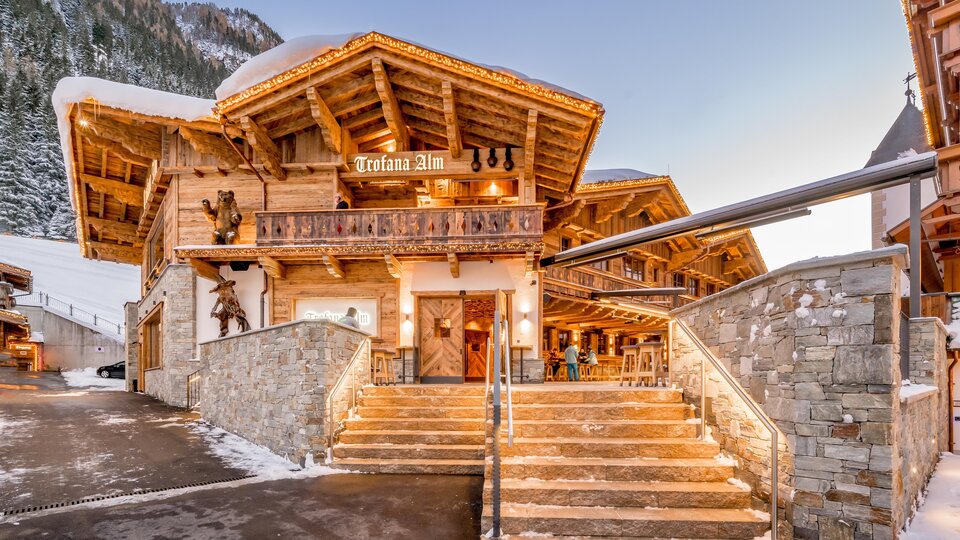 A charming alpine building with a wooden structure and an inviting entrance area. The snow around the house creates a wintry atmosphere.