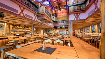 A rustic restaurant with wooden interiors and long tables. It is bright and inviting, ideal for social gatherings.
