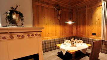A cozy dining area with wooden walls and a warm ambiance. The table is beautifully set, and a fireplace creates an inviting atmosphere.