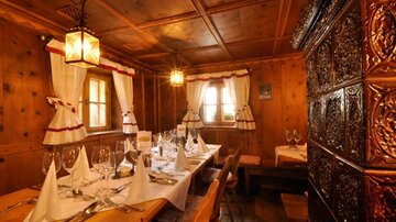 A cozy restaurant with wooden paneling and traditional decoration. The table is festively set and creates an inviting atmosphere.