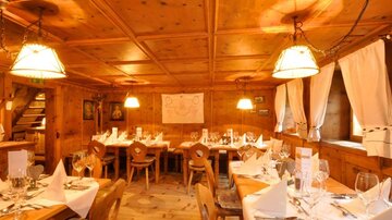 A cozy restaurant with wooden furniture and warm lighting. The tables are elegantly set and invite you to linger.