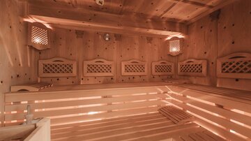 A Finnish sauna with wooden paneling and cozy lighting. The benches are made of light wood and provide space for relaxation.