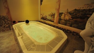 An elegant jacuzzi in a stylish room with a picturesque mural. The atmosphere is relaxing and cozy.