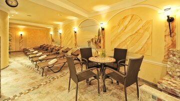 A relaxing wellness area with loungers and a small table. The walls are designed in warm, soothing colors.