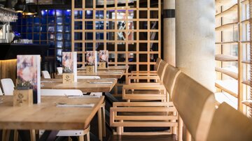A modern restaurant with wooden tables and chairs. The decor is stylish and feels inviting.
