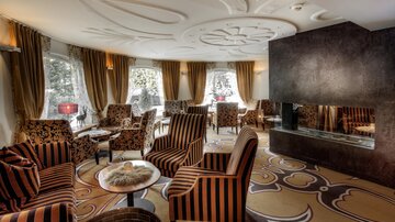 Eine stilvolle Lounge mit komfortablen Sesseln in Streifenmuster. Große Fenster sorgen für viel Tageslicht und eine gemütliche Atmosphäre.